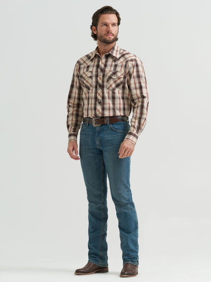 Man wearing a brown plaid Wrangler shirt and blue jeans on a white background