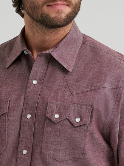 Close-up of a Wrangler maroon button-up shirt with a pocket and buttons on a neutral background