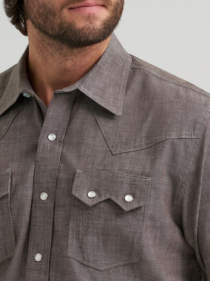 Close-up of a man wearing a Grey Wrangler button-up shirt with a neutral background