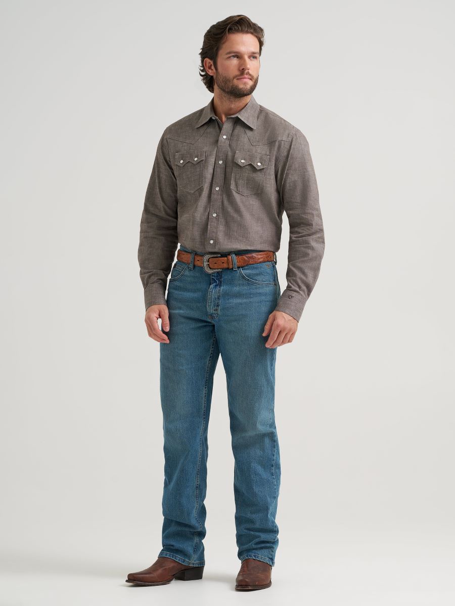 Man wearing a gray Wrangler shirt and blue jeans on a white background