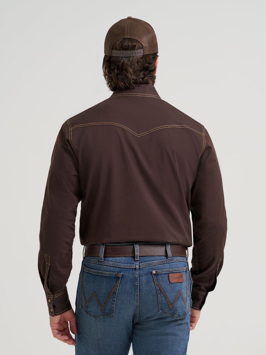 Man wearing a brown long-sleeve Wrangler shirt and blue jeans with a cap on a white background