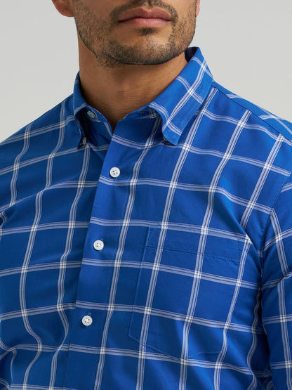 Close-up of a person wearing a blue checkered Wrangler shirt with a neutral background