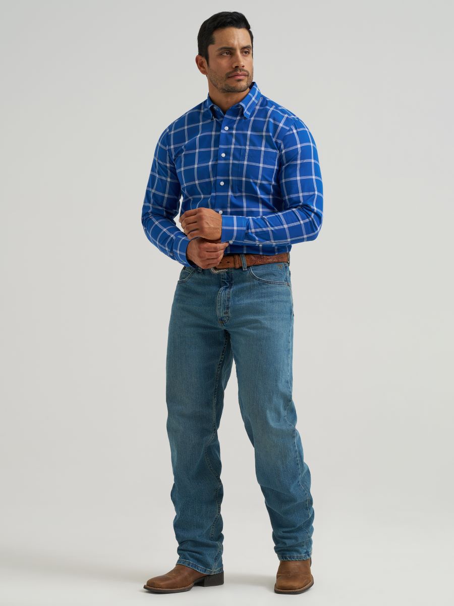 Man wearing a blue plaid Wrangler shirt and jeans on a gray background
