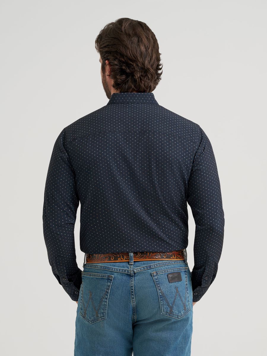 Man wearing a dark blue patterned Wrangler shirt and jeans on a light gray background