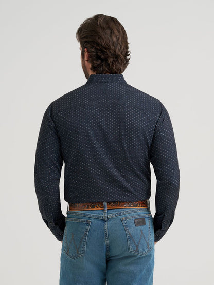 Man wearing a dark blue patterned Wrangler shirt and jeans on a light gray background