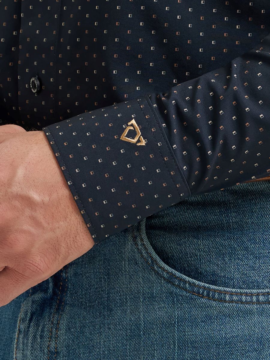 Close-up of a navy blue Wranlgler shirt with gold pattern and cufflinks, paired with blue jeans.