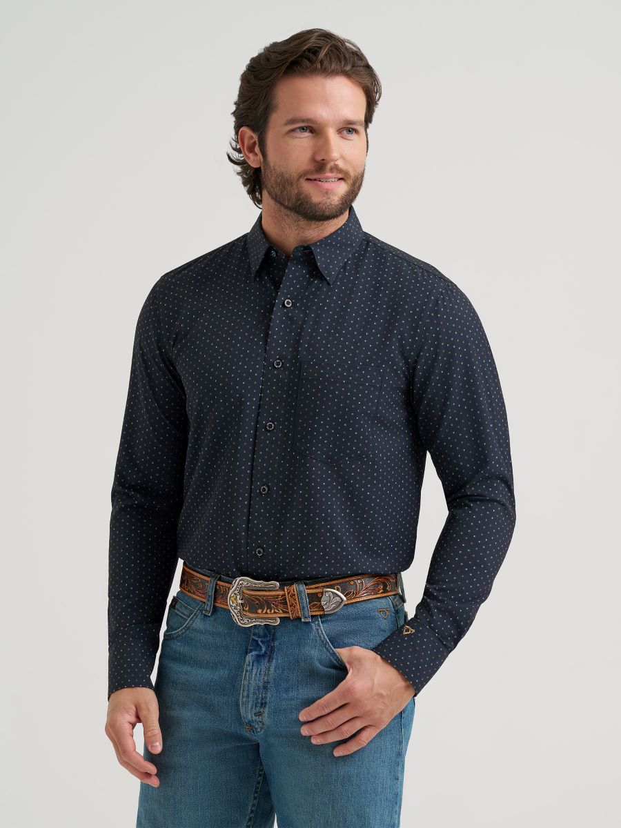 Man wearing a dark blue patterned Wrangler shirt and jeans on a light gray background