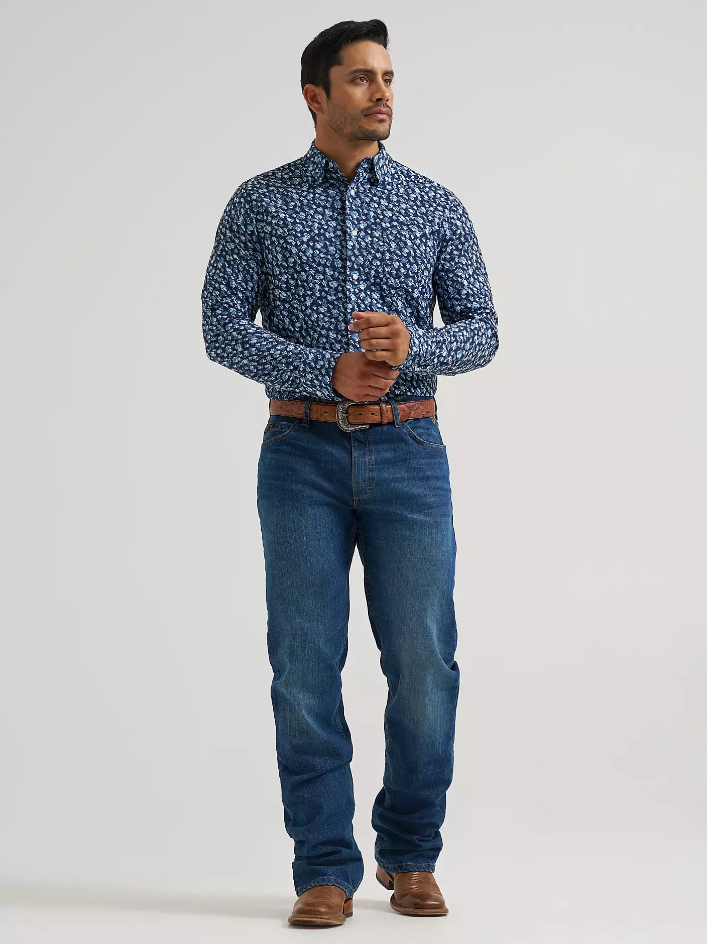 Man wearing a blue Wrangler shirt and blue jeans on a white background