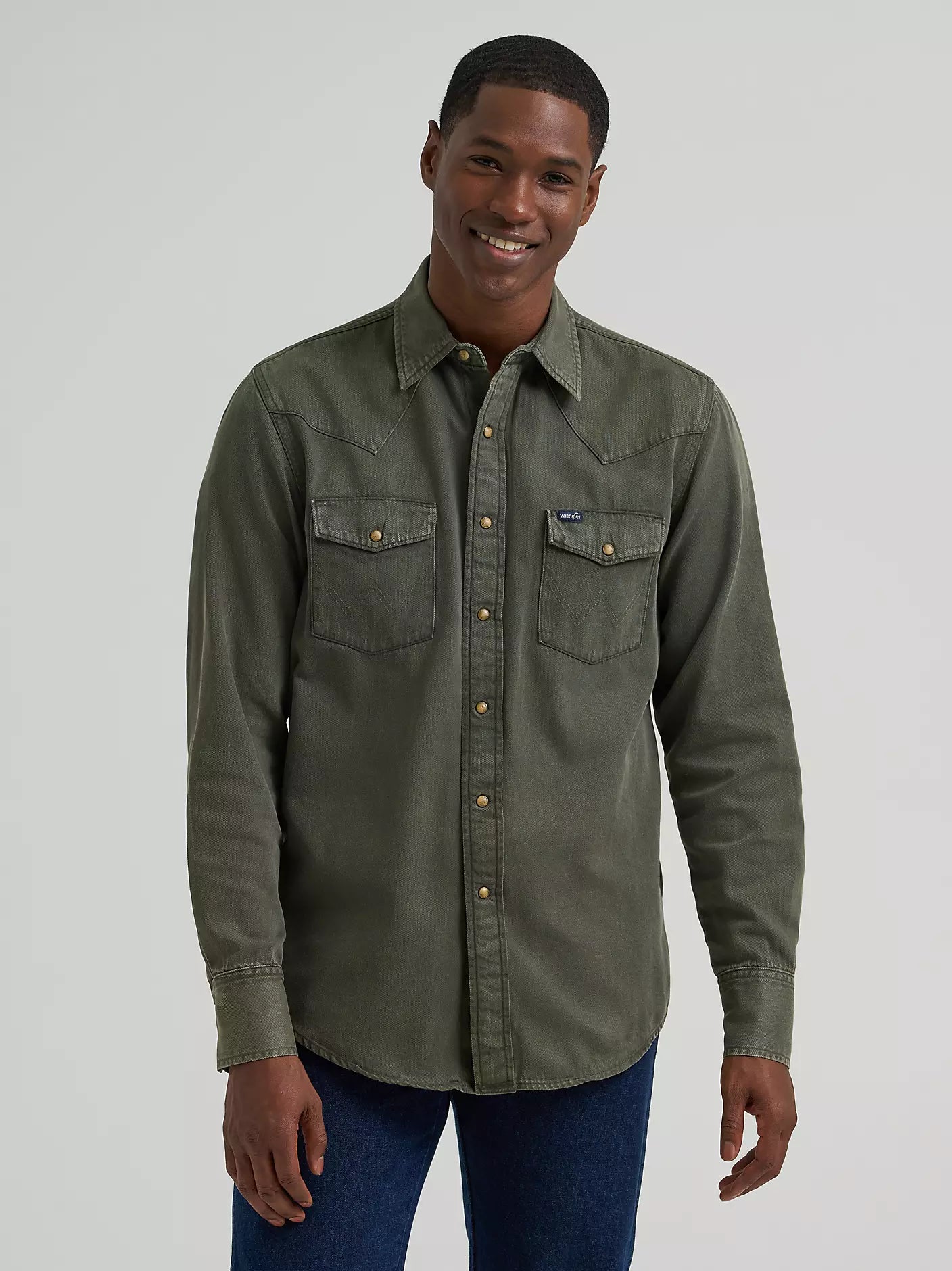 man wearing a green denim Wrangler shirt and blue jeans on a white background