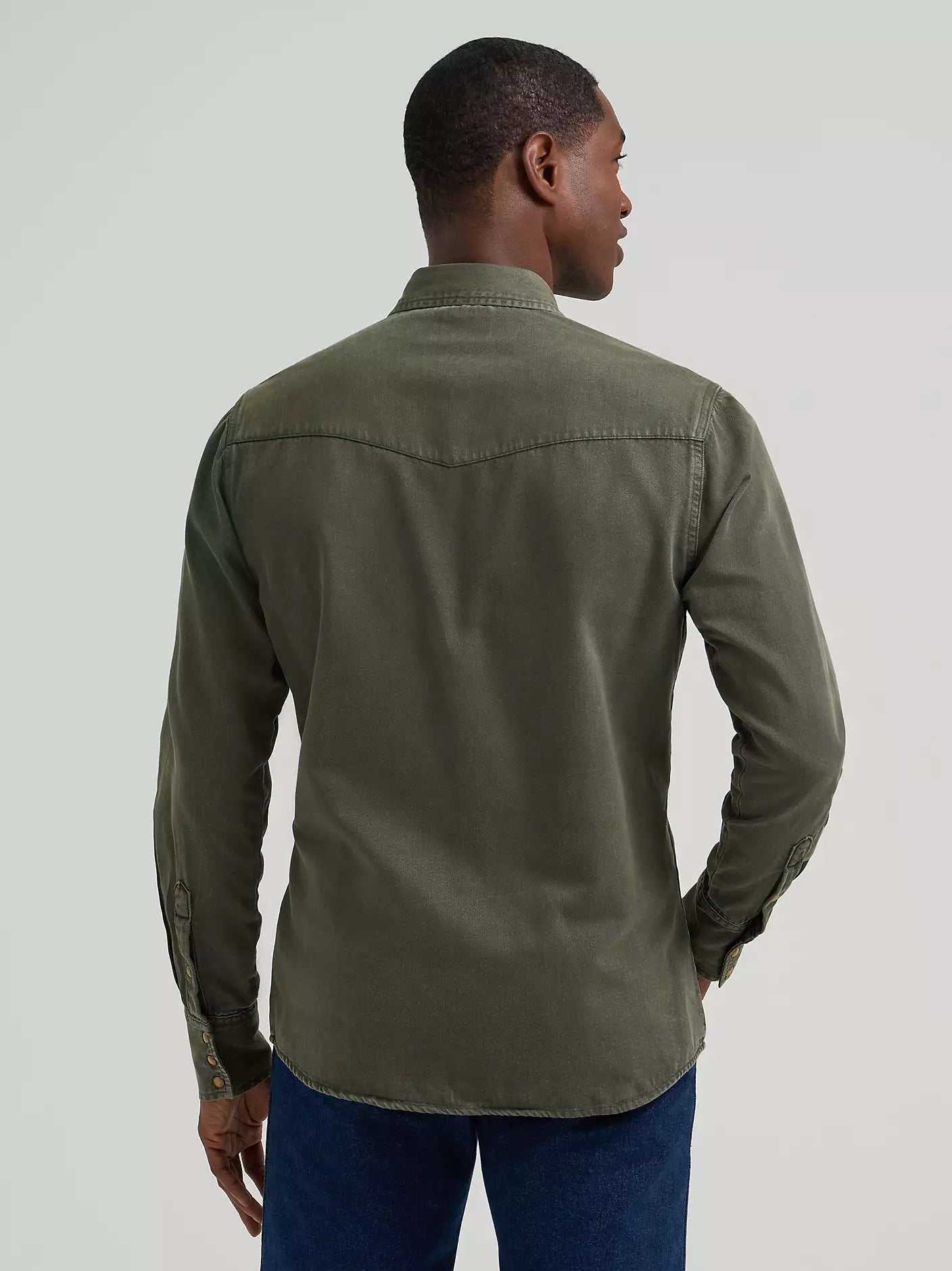 man wearing a green denim Wrangler shirt and blue jeans on a white background
