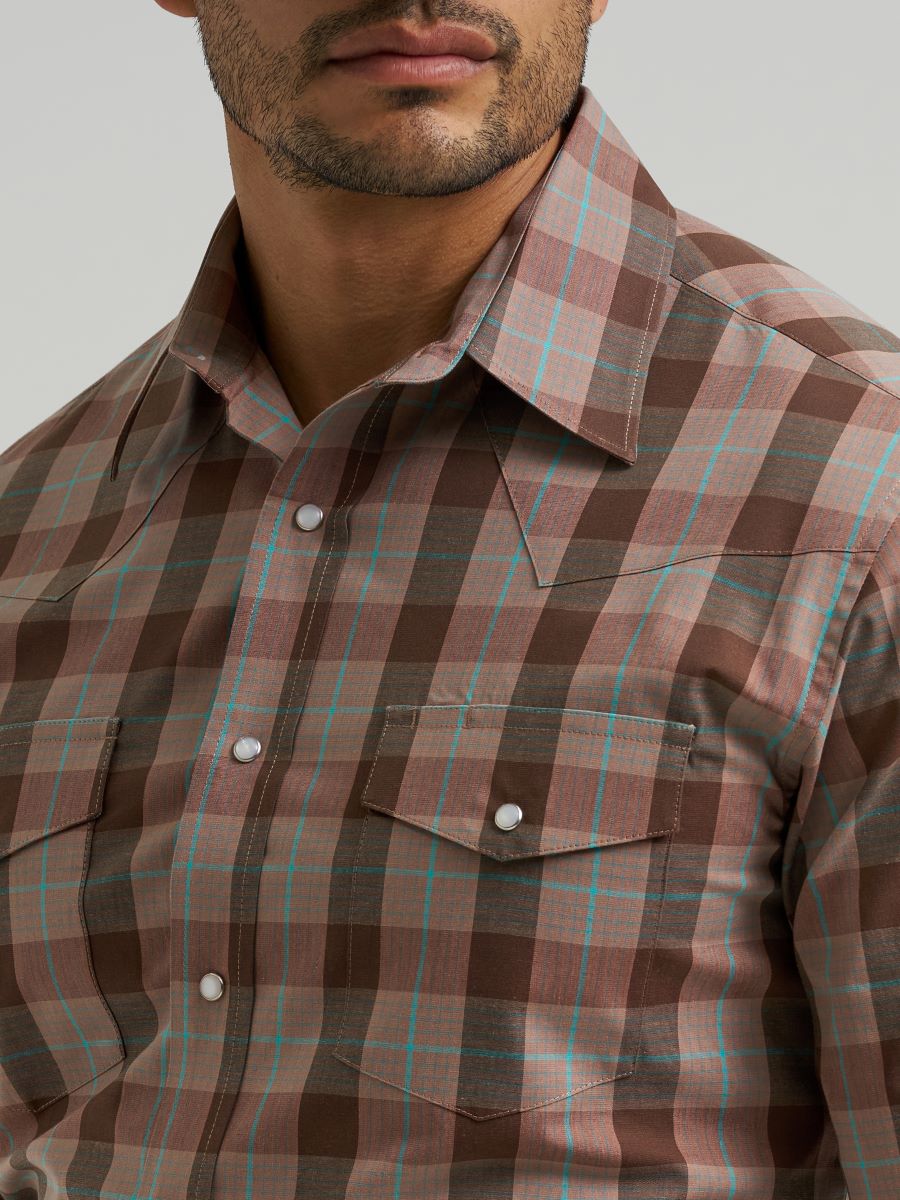 Close-up of a man wearing a brown plaid Wrangler shirt with a neutral background
