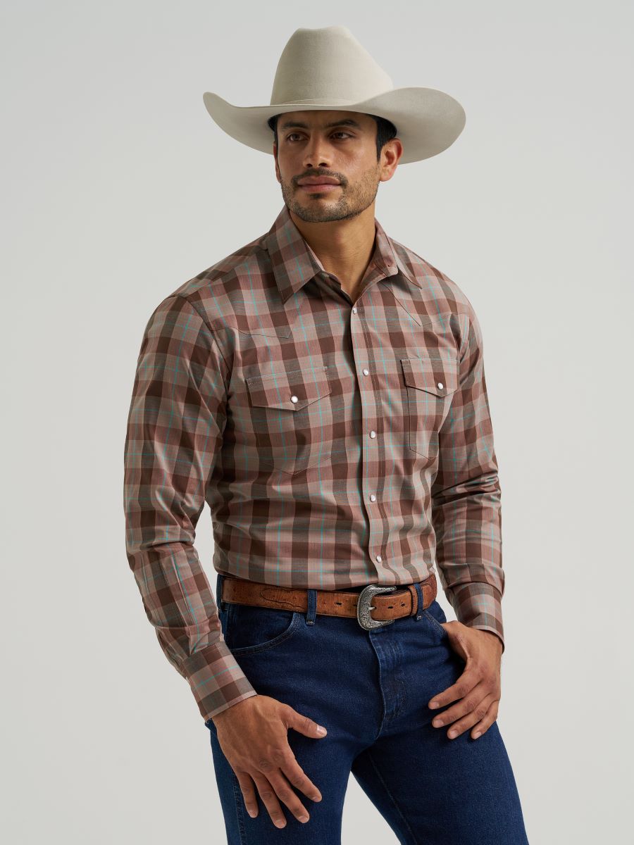 Man wearing a plaid Wrangler shirt, jeans, and a cowboy hat on a plain background