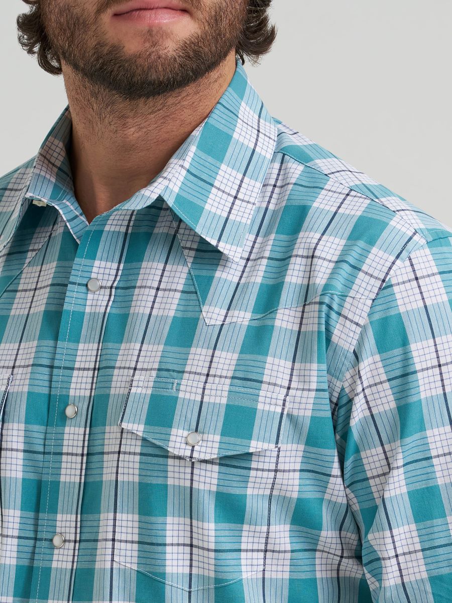 Close-up of a person wearing a blue and white checkered Wrangler shirt against a gray background