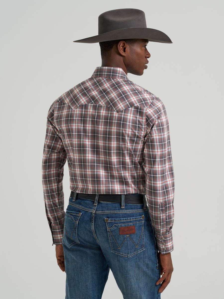 Man wearing a plaid Wrangler shirt and cowboy hat on a gray background