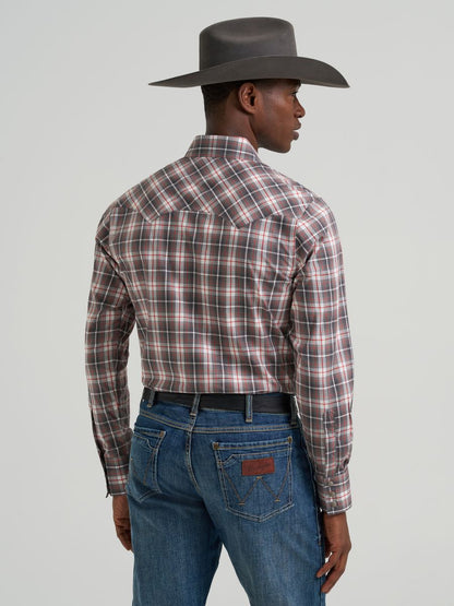 Man wearing a plaid Wrangler shirt and cowboy hat on a gray background