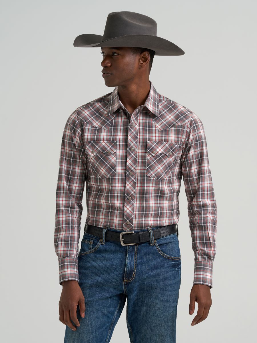 Man wearing a plaid Wrangler shirt, jeans, and a cowboy hat on a gray background