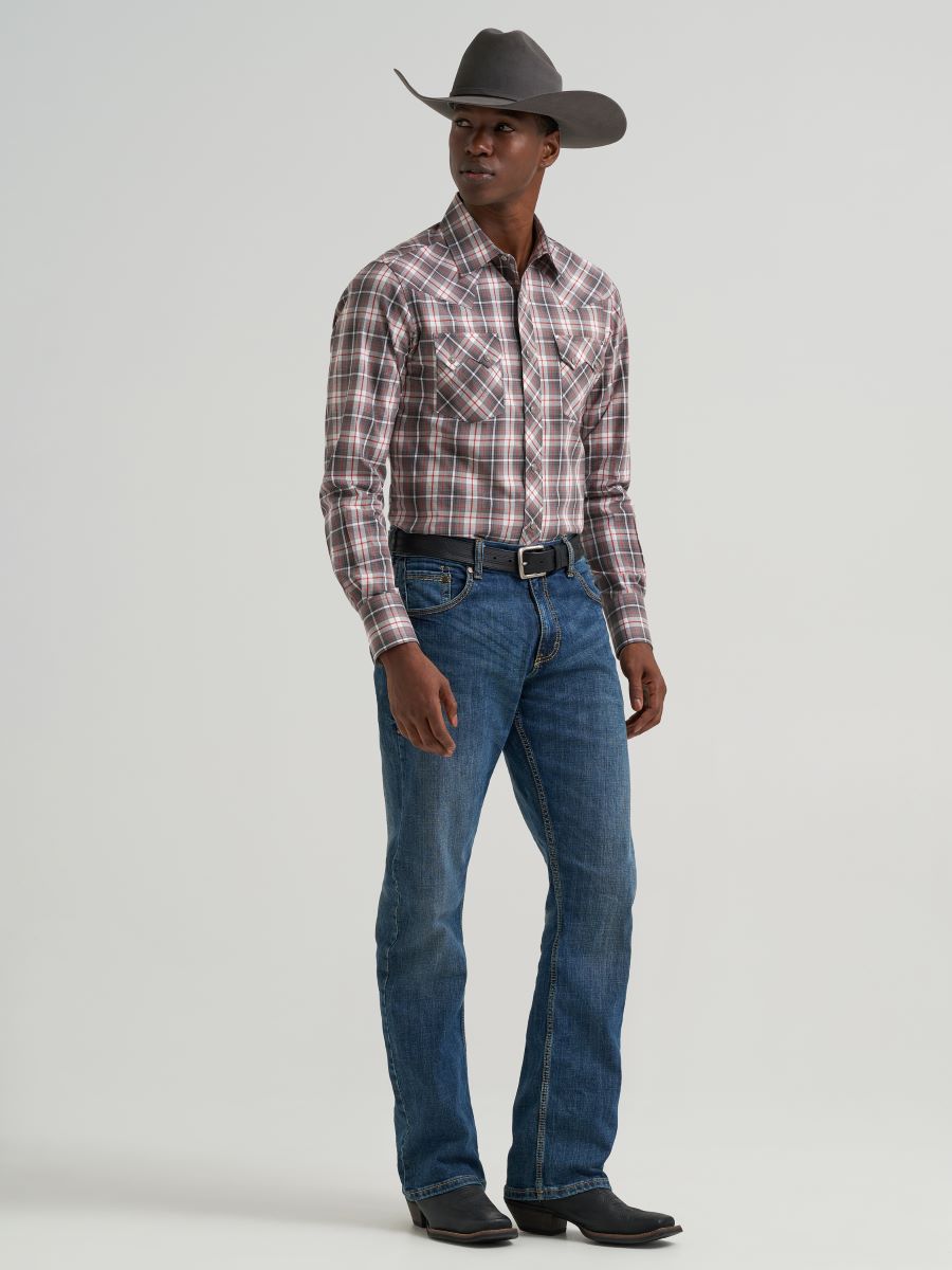 Man wearing a plaid Wrangler shirt, jeans, and a cowboy hat on a gray background