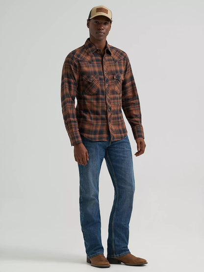 man wearing a brown plaid Wrangler flannel shirt, blue jeans and a ball cap on a grey background