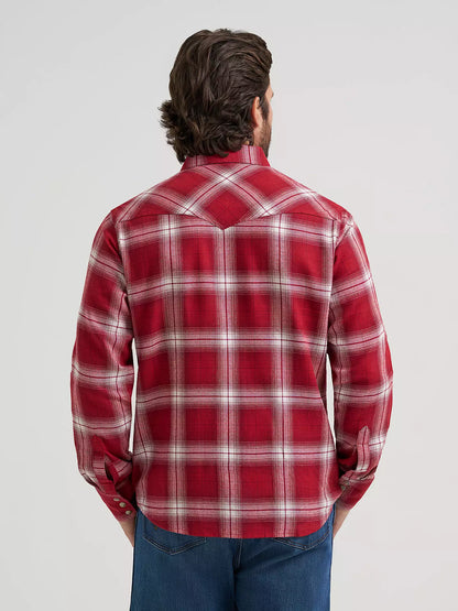 man wearing a red plaid flannel by Wrangler and blue jeans on a grey background