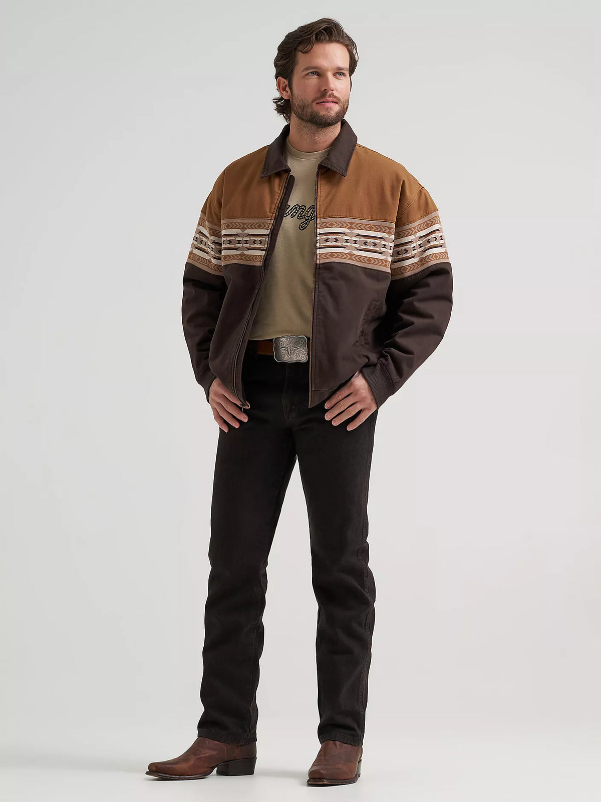 Man wearing a brown Wrangler bomber jacket and black jeans on a white background