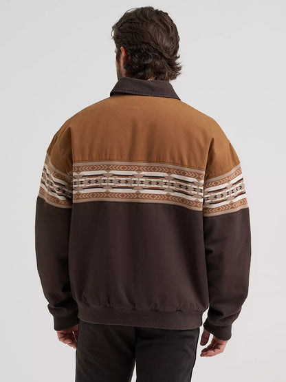 Man wearing a brown Wrangler bomber jacket and black jeans on a white background