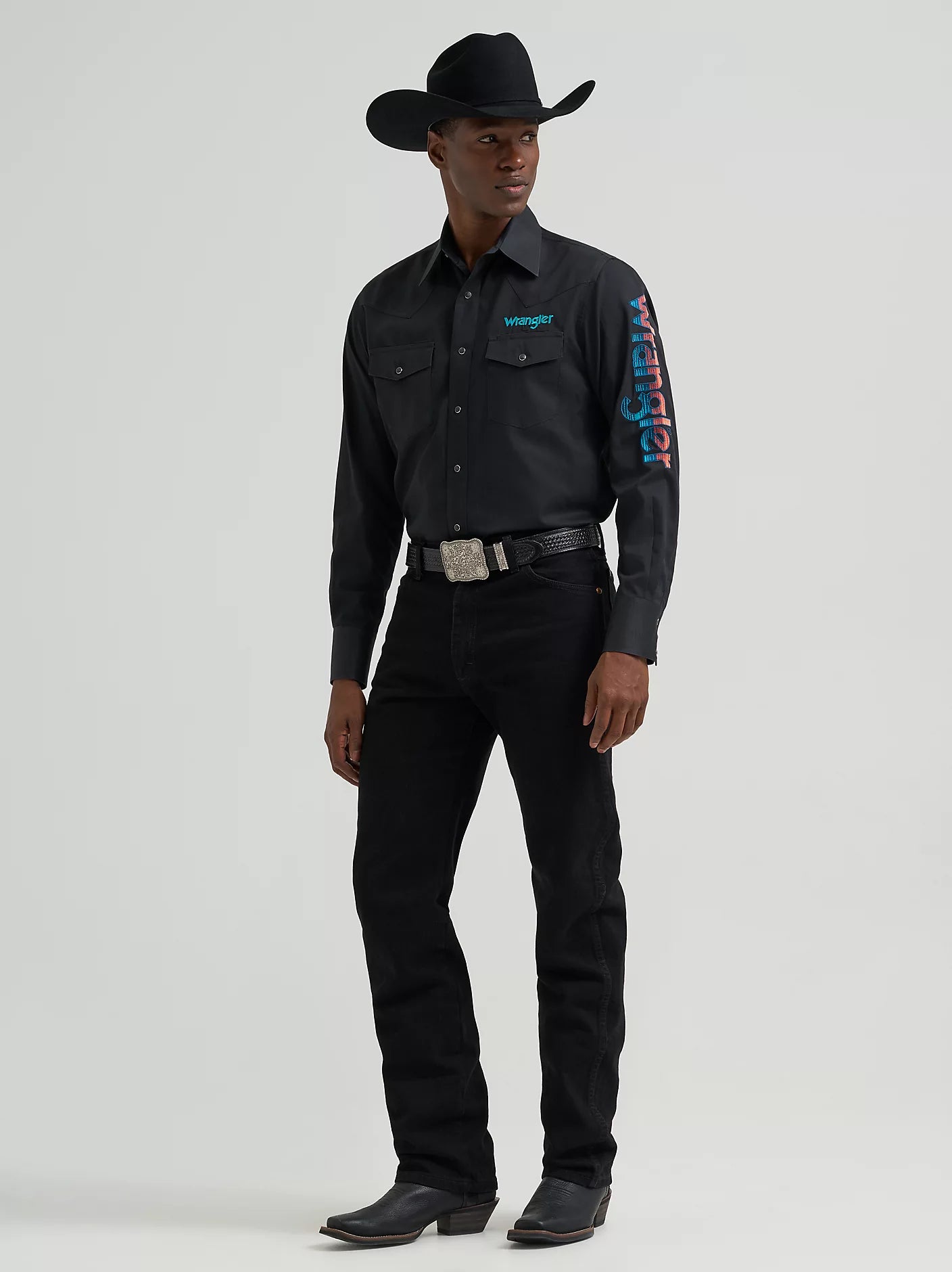 Person wearing a black Wrangler shirt with branding on a gray background