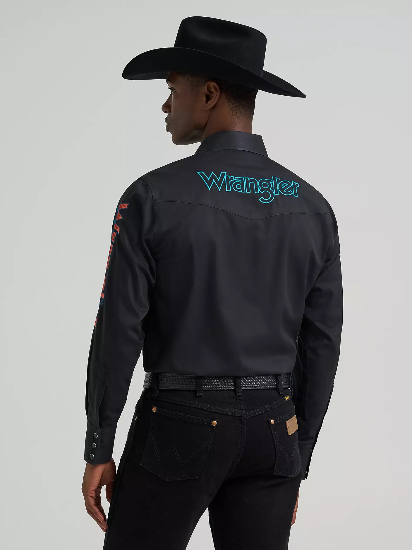 Person wearing a black Wrangler shirt with branding on a gray background