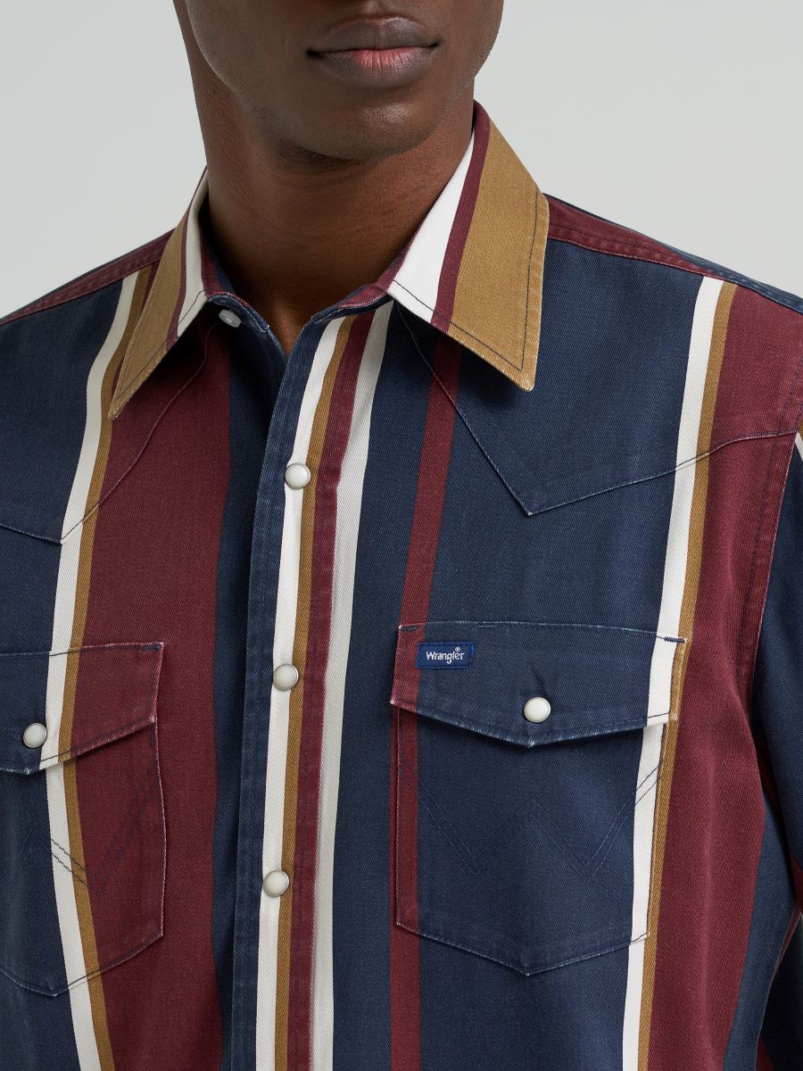 Close-up of a person wearing a striped Wrangler shirt with a brand logo on a plain background