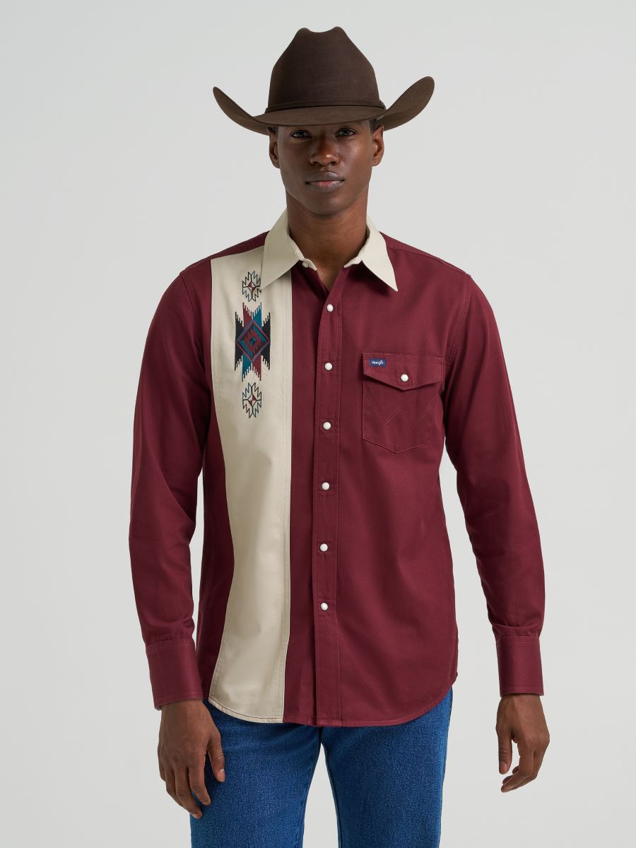 Man wearing a maroon and beige long-sleeve Wrangler shirt with a cowboy hat on a white background 