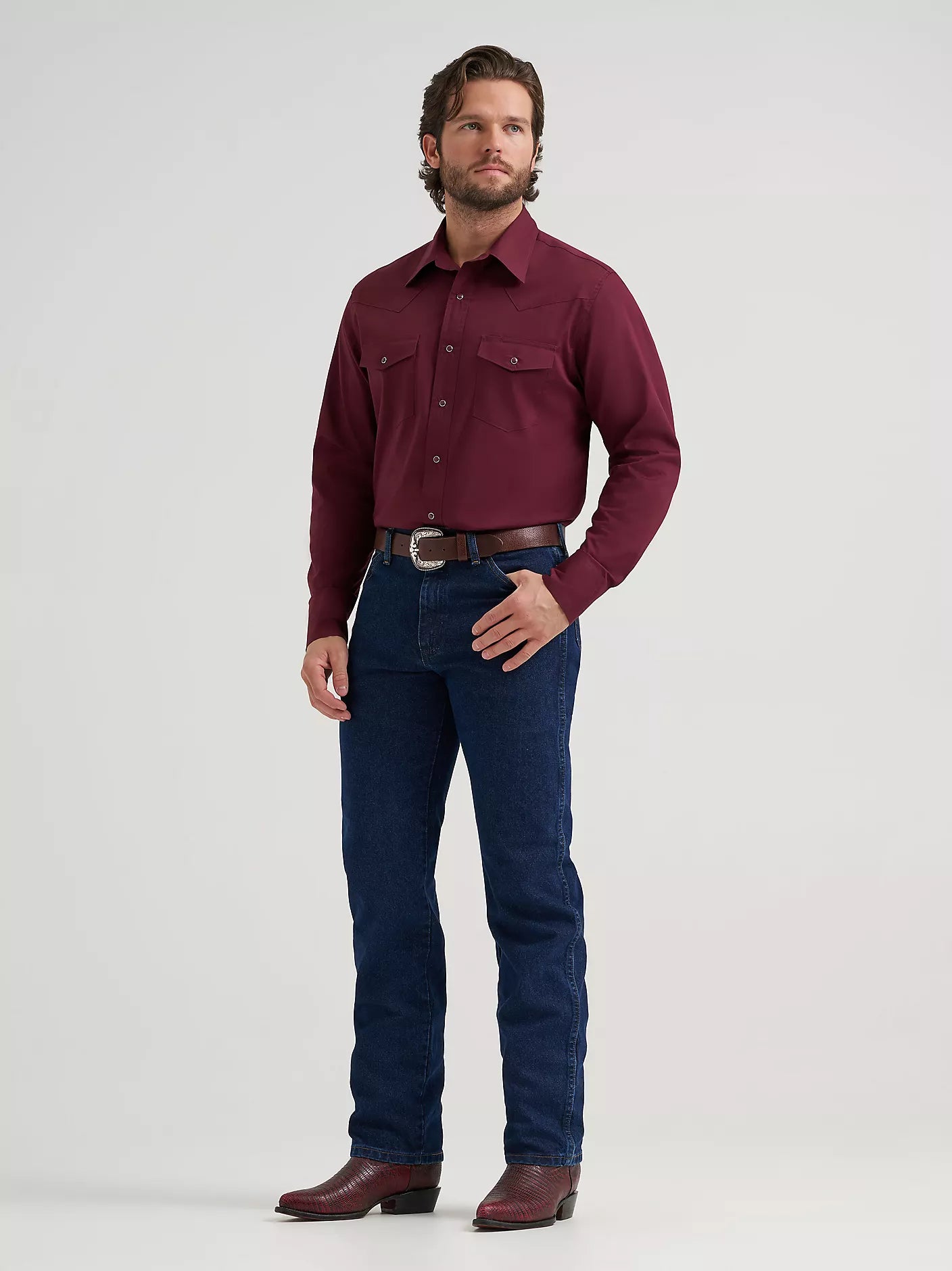 man wearing a burgundy Wrangler shirt, blue jeans and boots on a white background