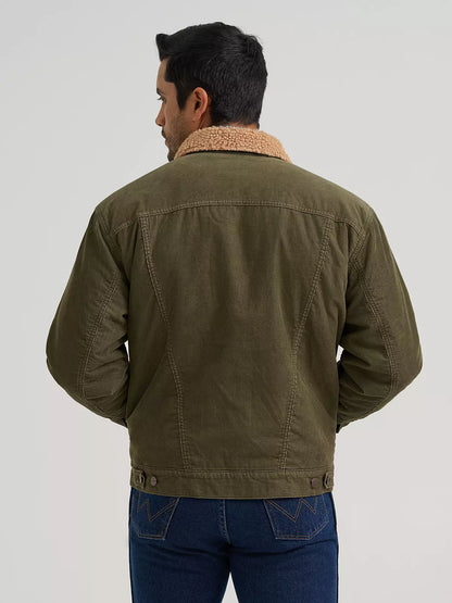 A man viewed from the back wearing an olive green Wrangler jacket with a tan sherpa collar, paired with blue jeans, against a light gray studio background.