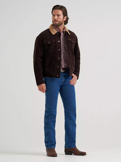 A man wearing a dark brown corduroy Wrangler jacket with a tan corduroy collar, blue jeans, and brown boots, standing against a light gray studio background.
