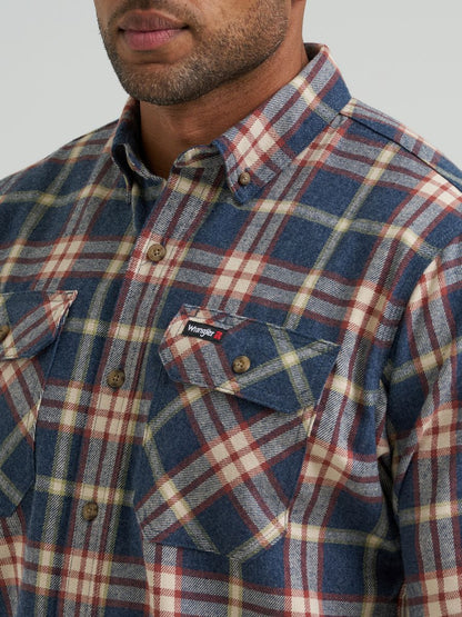 Close-up of a man wearing a long-sleeve plaid button-down shirt by Wrangler, featuring a blue, red, and beige check pattern with a chest pocket and visible Wrangler logo tab.