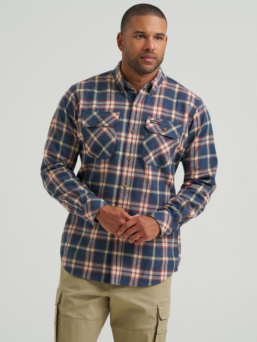 A man wearing a long-sleeve button-down Wrangler plaid shirt in navy blue, red, and beige, paired with khaki cargo pants, against a light gray studio background.