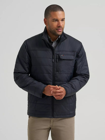 A man wearing a black Wrangler quilted jacket with a zippered chest pocket, standing against a light gray studio background.