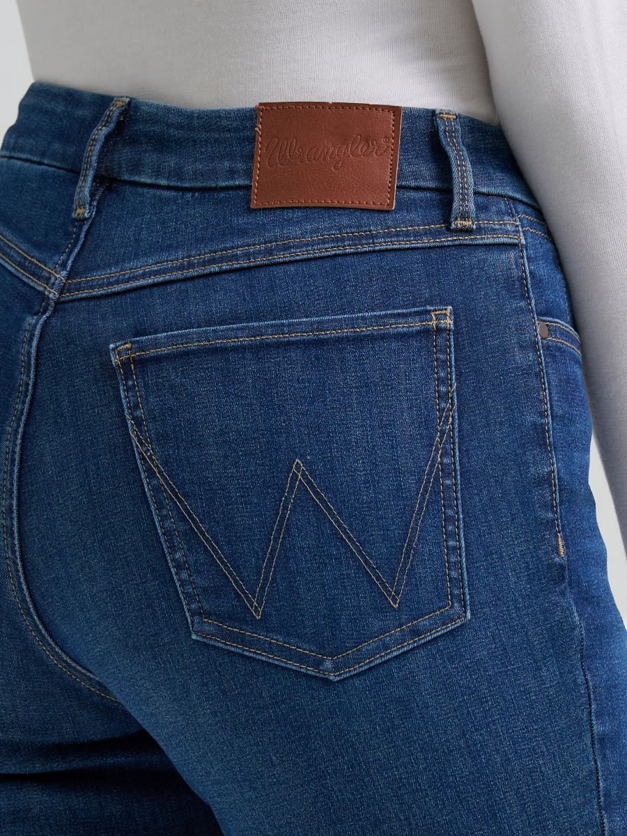 Person wearing blue Wrangler jeans on a white background
