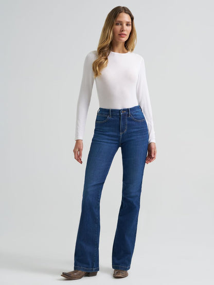 Woman wearing blue Wrangler jeans and a white long-sleeve top on a light gray background