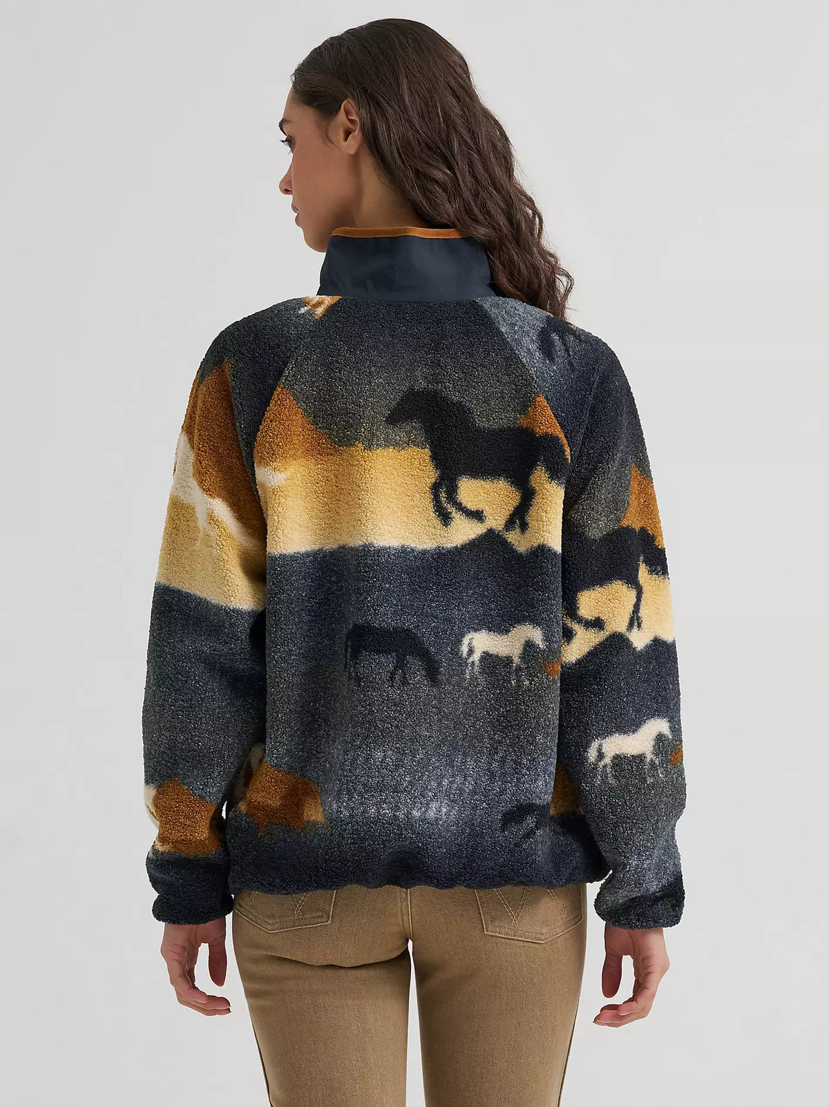 woman wearing a sherpa fleece Wrangler sweater and brown jeans on a white background