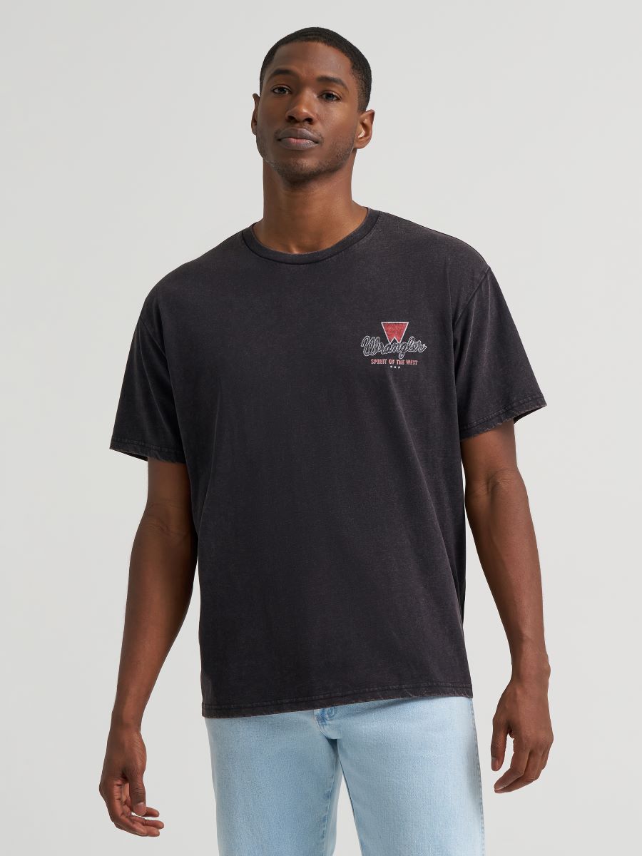 man wearing a black Wrangler tshirt and blue jeans on a grey background