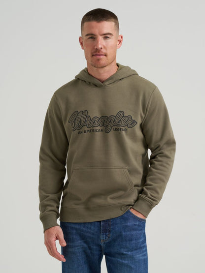 Man wearing a green Wrangler hoodie and blue jeans on a grey background