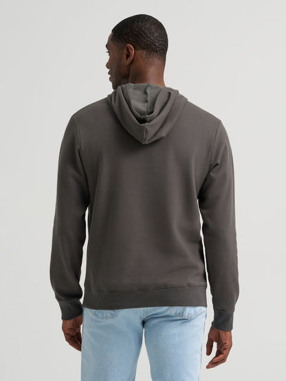 Man wearing a grey Wrangler hoodie and blue jeans on a grey background