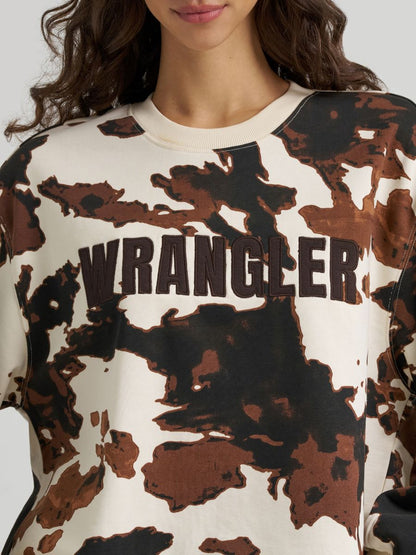 Close up of a woman wearing a cow print Wrangler sweate on a grey background