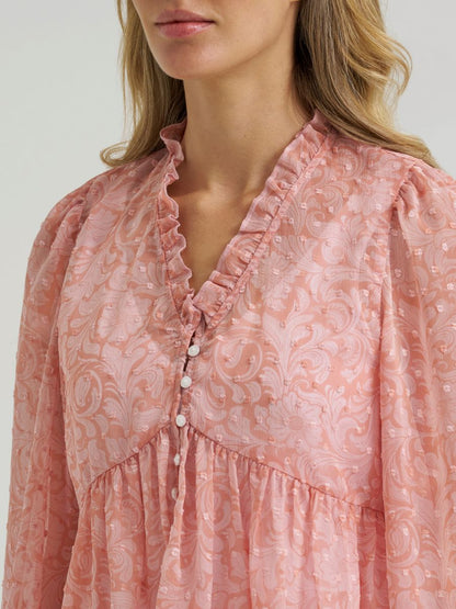 Woman wearing a sheer pink Wrangler blouse on a grey background