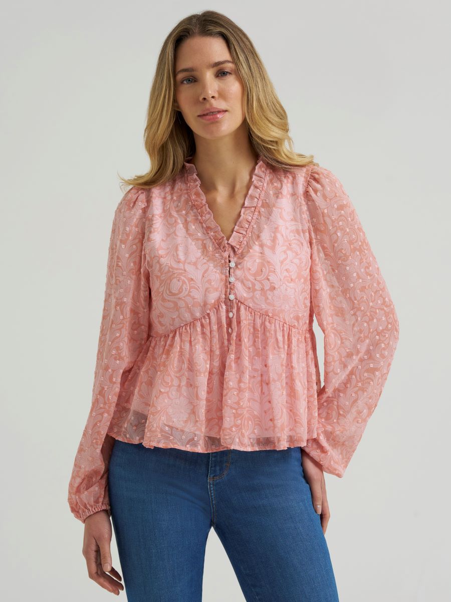 Woman wearing a sheer pink Wrangler blouse and blue jeans on a grey background