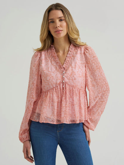 Woman wearing a sheer pink Wrangler blouse and blue jeans on a grey background
