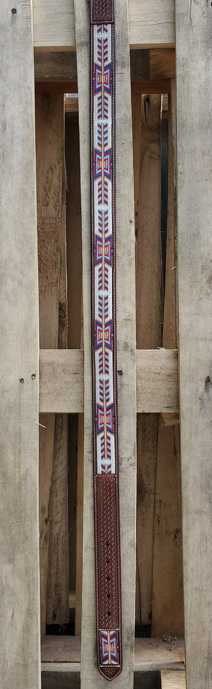 Lengthwise view of a leather belt with a 'fletching' design on a wooden background