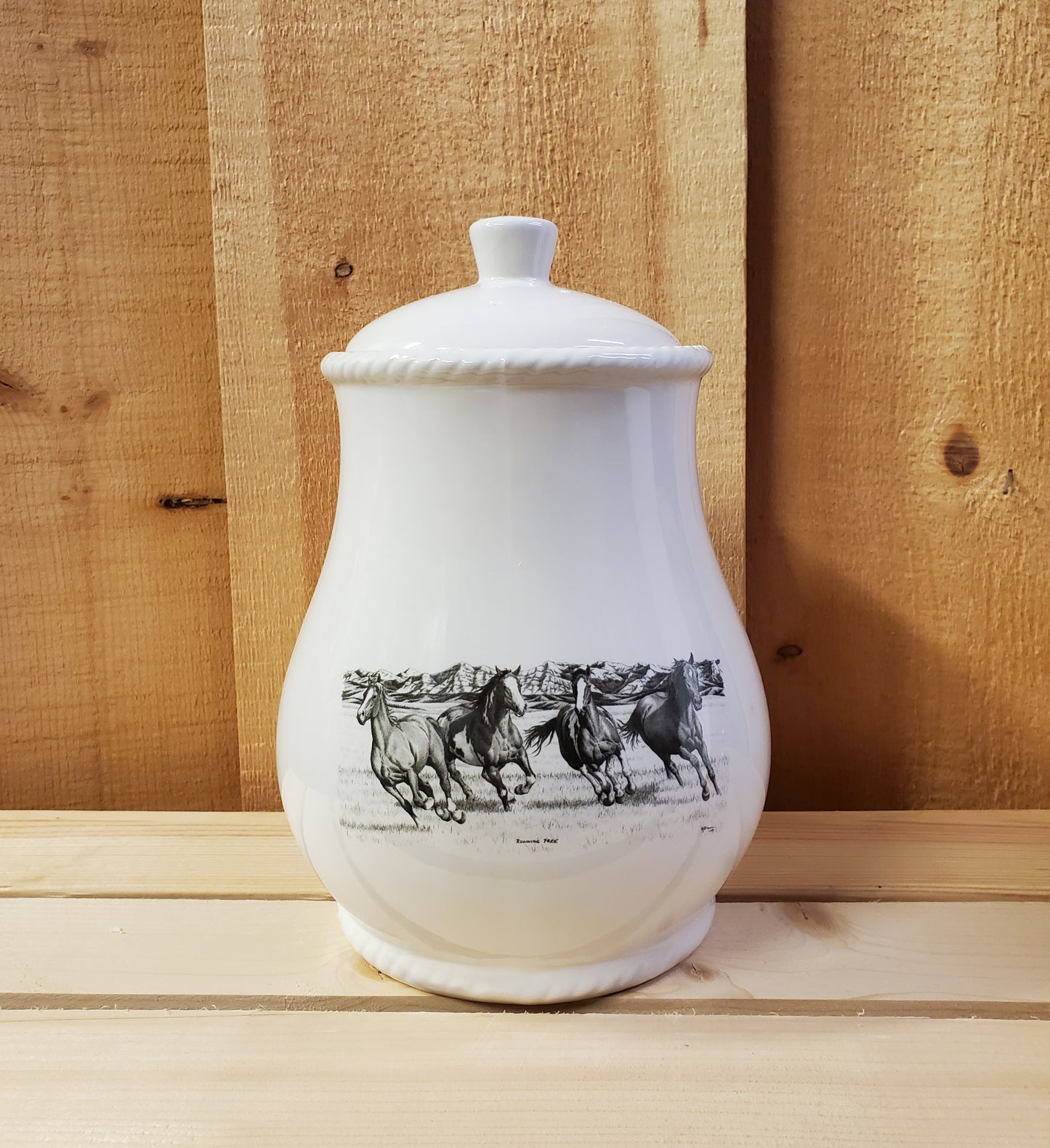 A white cookie jar with a lid, featuring a black and gray pencil art depiction of running horses