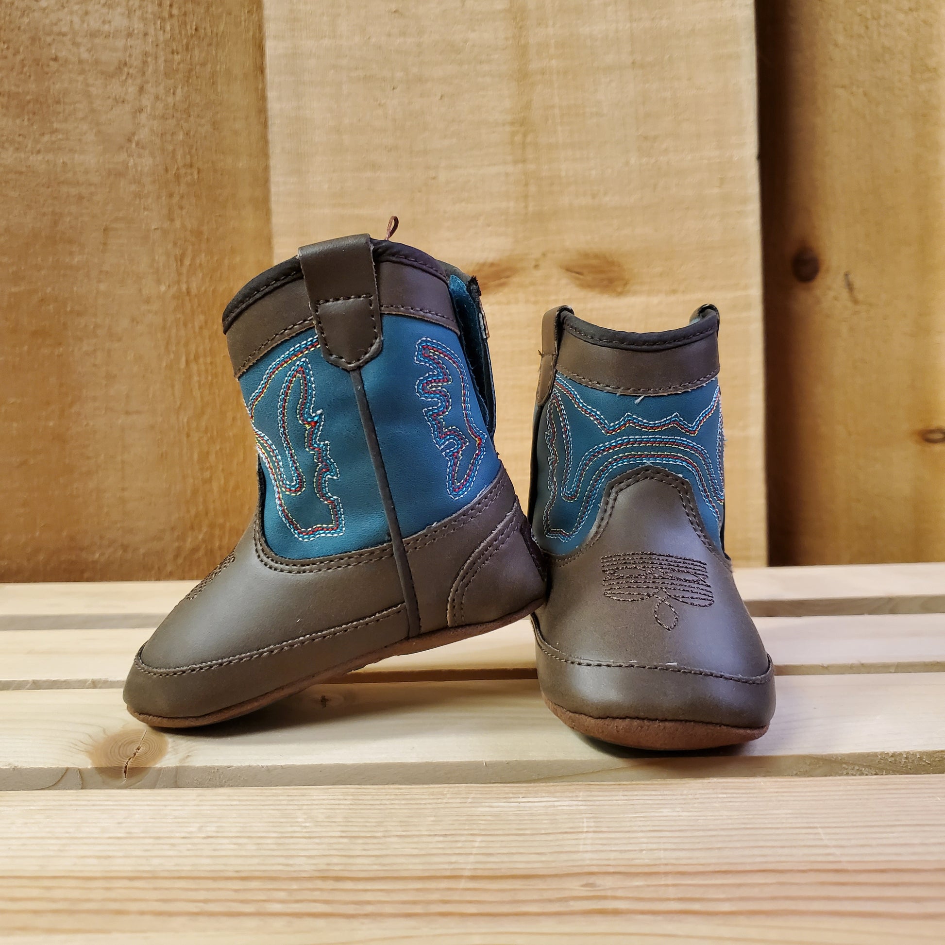 Blue and brown baby boots by twister on a wooden background