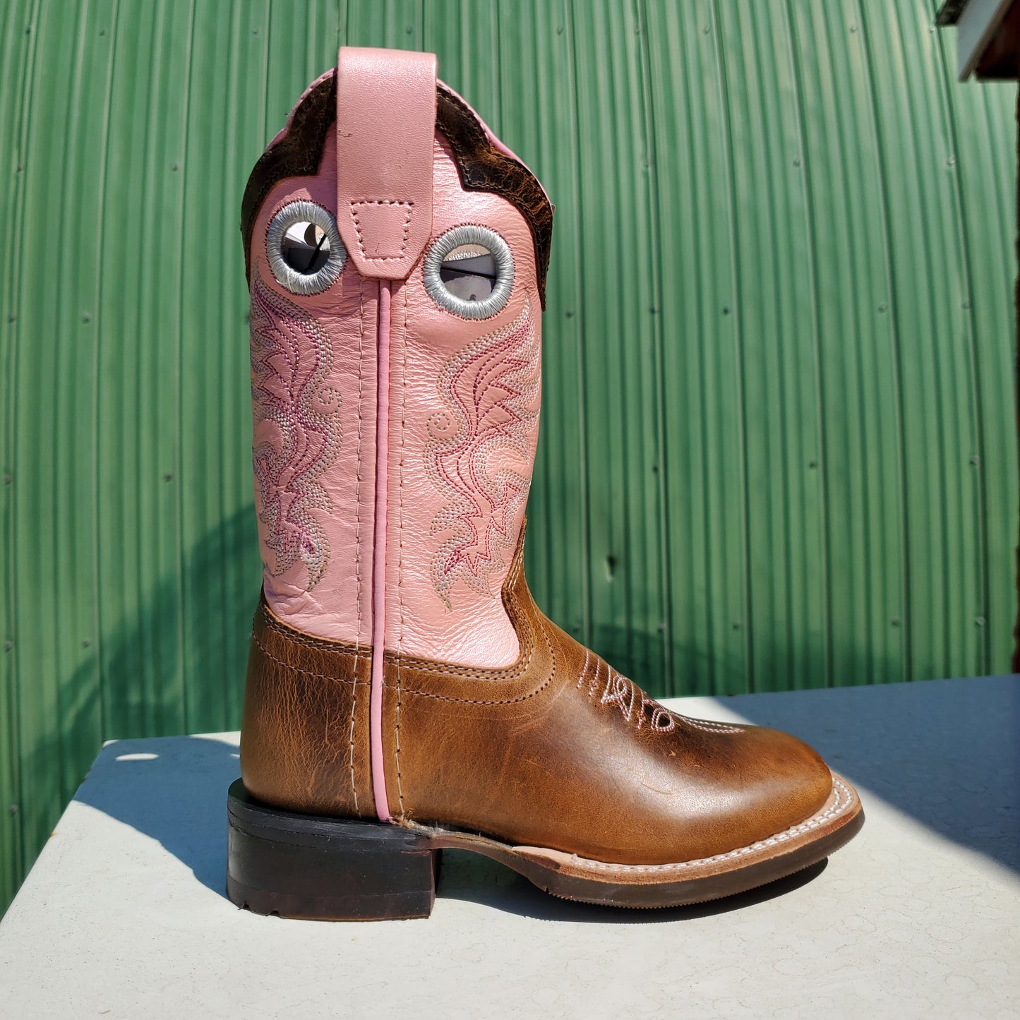 A children's boot with pink upper and brown toe, featuring a leather foot and rubberized outsole.