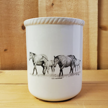 a white ceramic utensil holder with western pencil art featuring two mares and two foals